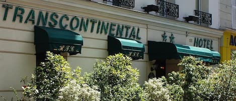 Fachada de hotel con balcones, un letrero que dice "HOTEL" y el nombre "TRANSCONTINENTAL" sobre la entrada.