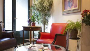 A modern living room with a glass coffee table, red leather sofa, and a large potted plant. - Hotel Transcontinental (Paris)