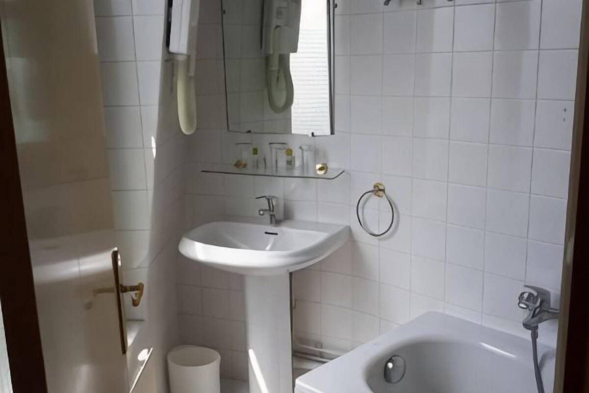 A bathroom with a white sink, a mirror, a bathtub, and a toilet.