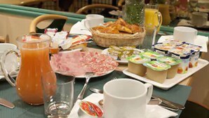 A breakfast table with various food items, a pitcher of orange juice, and a vase with flowers. - Hotel Transcontinental (Paris)