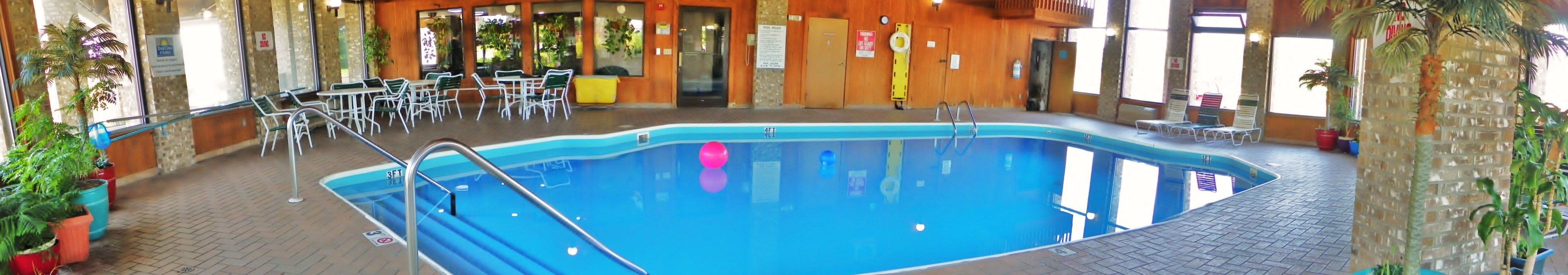 An indoor swimming pool with a 3ft depth marker, surrounded by lounge chairs and potted plants.