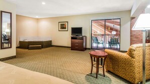 Habitación de hotel con una bañera grande, televisor, escritorio y sofá.