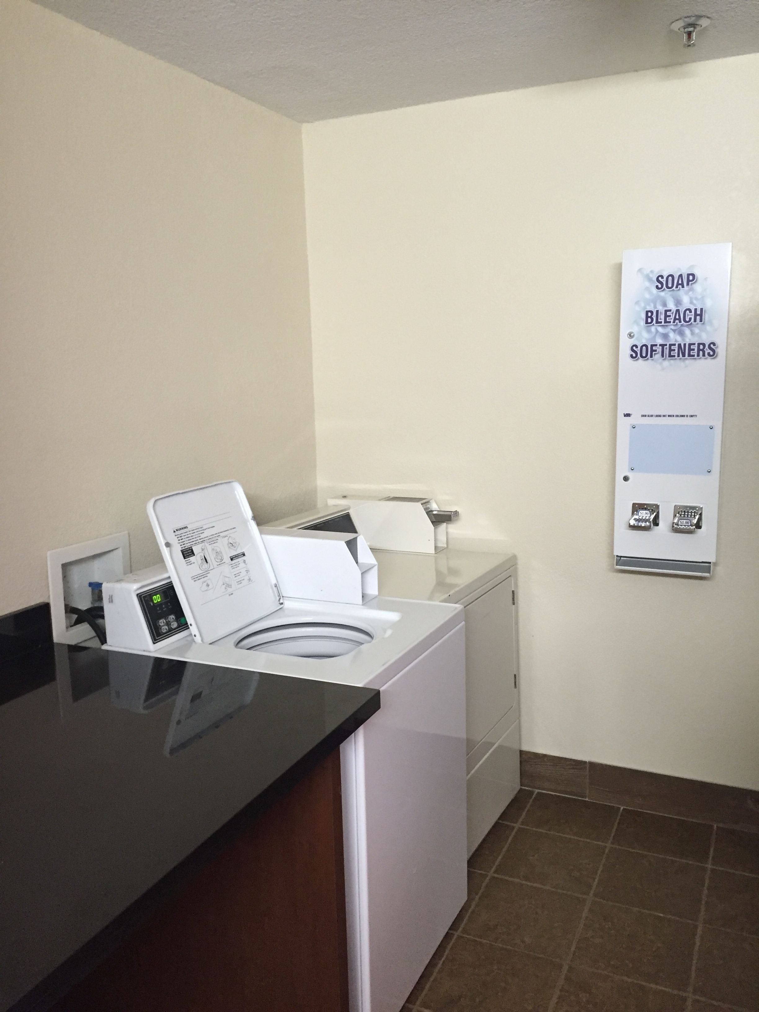 A laundry area with a washing machine, dryer, and a sign listing soap, bleach, and softeners.