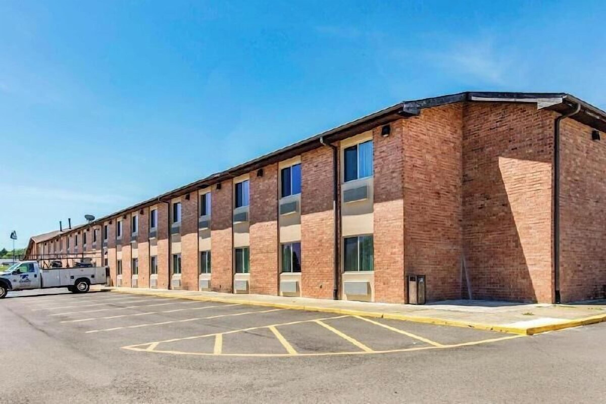 A long brick building with multiple windows and a parking lot in front.