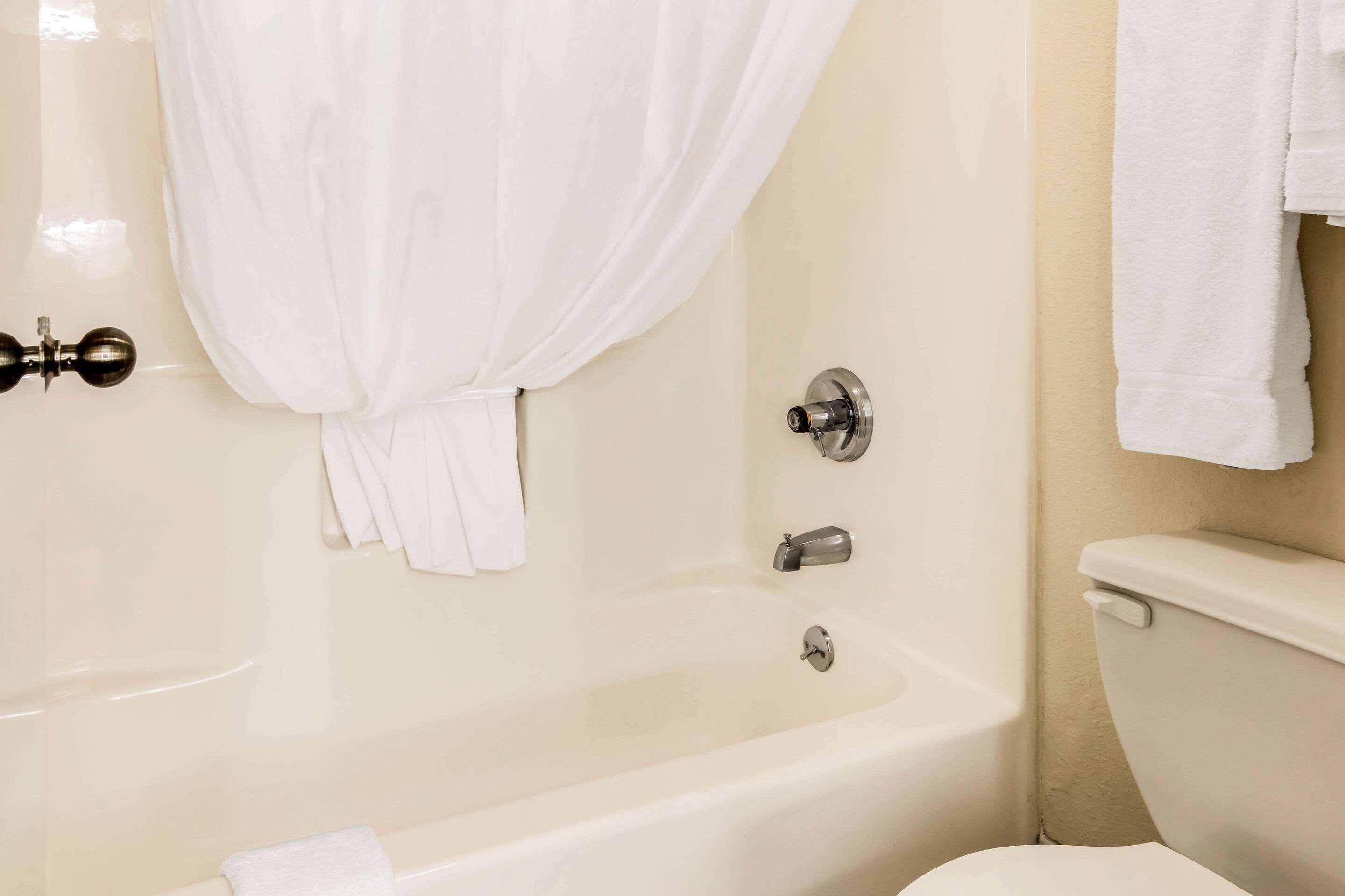 A bathroom with a bathtub, toilet, and a curtain.