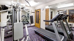 Une salle de sport équipée de matériel d’exercice, d’un tapis de course et d’un tapis à motifs.
