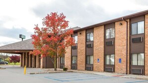 A multi-story building with a brick facade, a covered parking area, and a tree with autumn foliage.