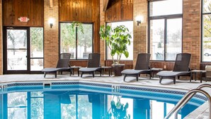 An indoor swimming pool with lounge chairs and potted plants.