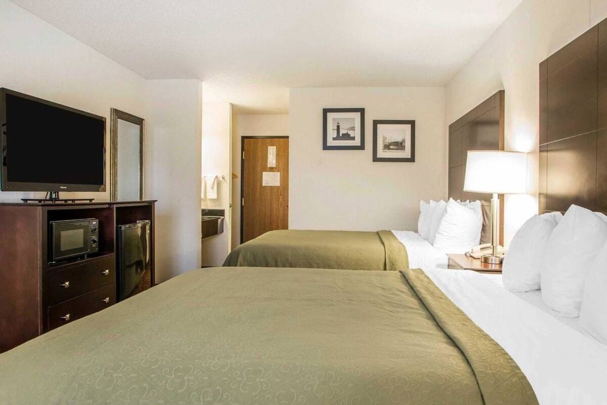 Una habitación de hotel con dos camas, televisión, microondas y refrigerador.