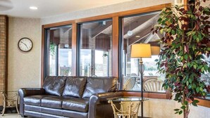 Una sala de estar con un sofá de cuero, una mesita, una lámpara y un ventanal grande.