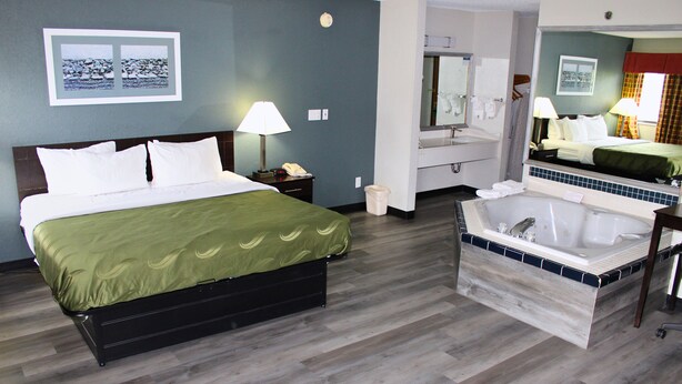 A hotel room with a bed, a bathroom with a bathtub, and a mirror. - Blisspoint Inn Columbia City (Columbia City)