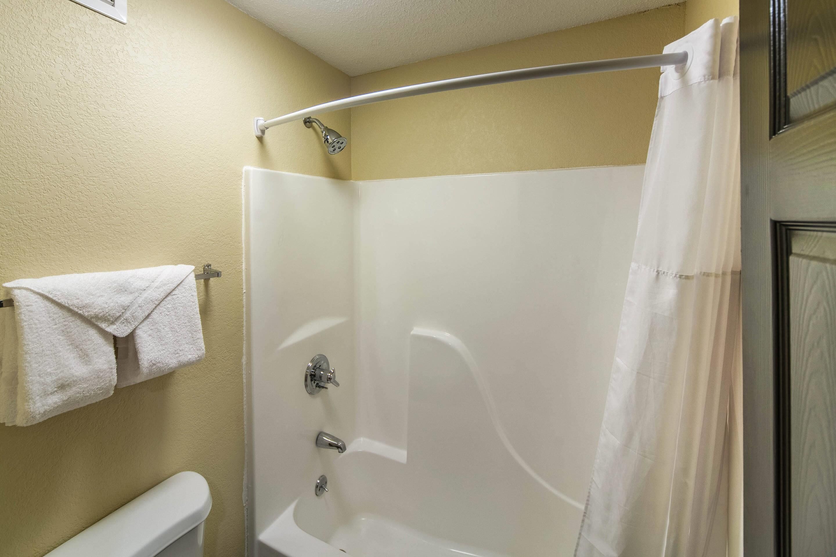A bathroom with a white bathtub, a shower curtain, and a towel hanging on a rack.