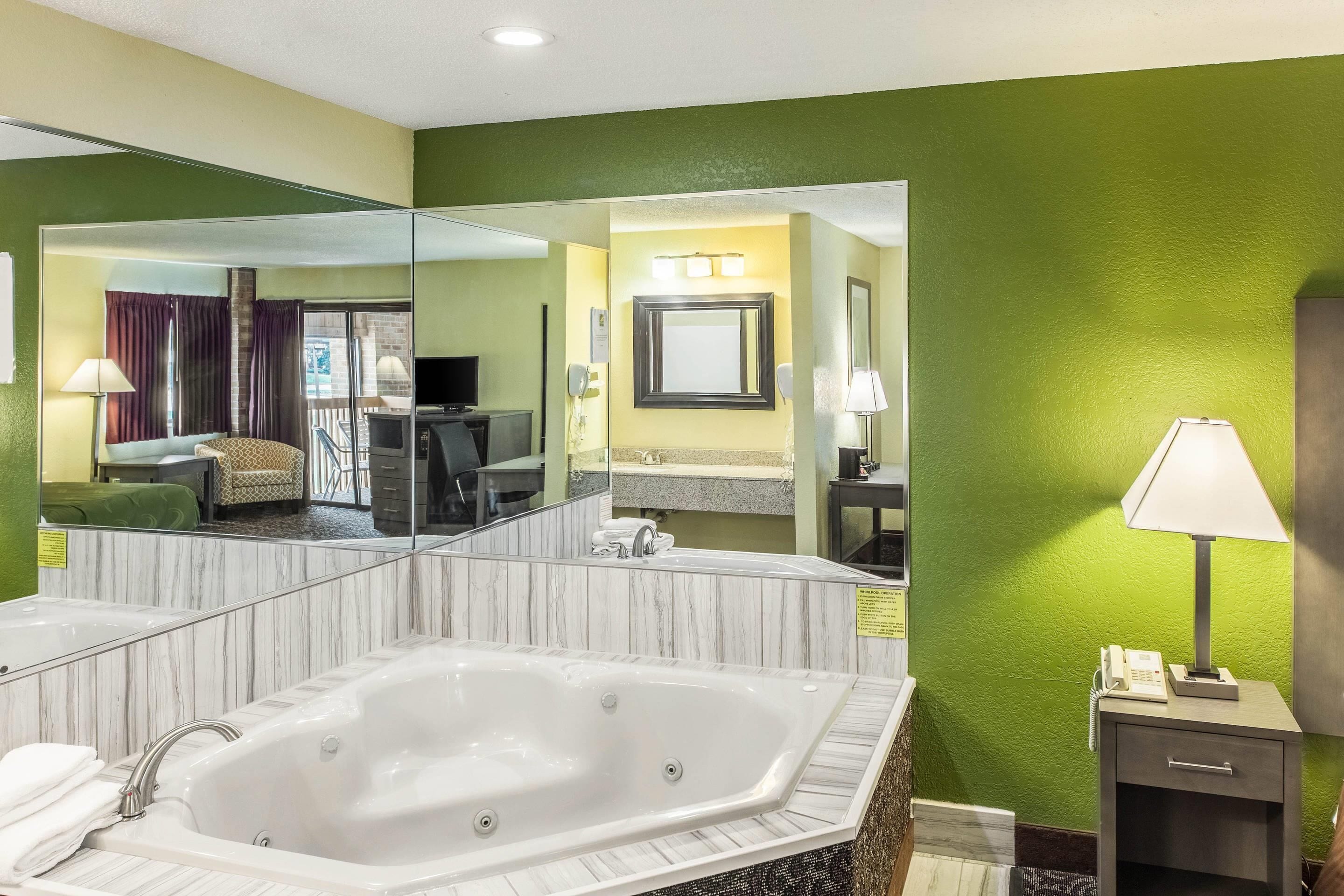 Un baño de hotel con un espejo grande, una bañera, un lavamanos y un tocador.