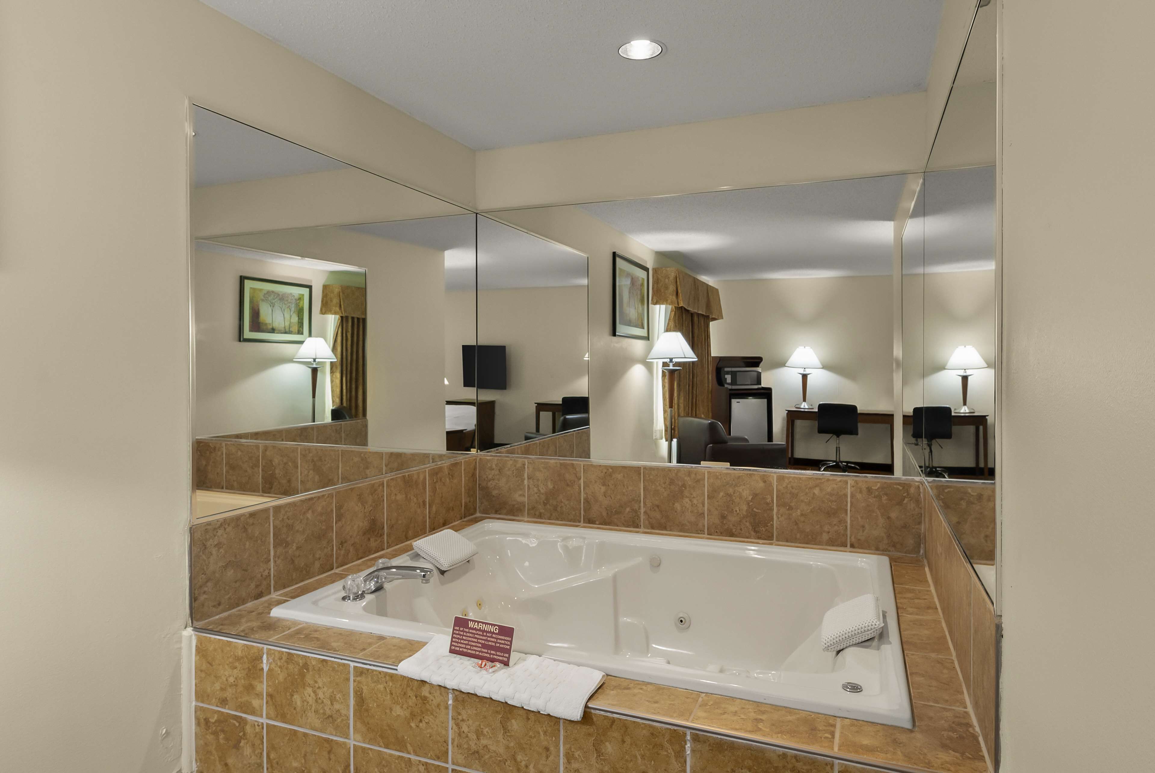 A modern bathroom with a large bathtub, a mirror, and a sink.
