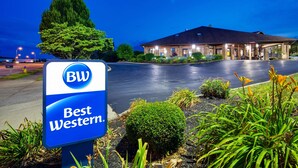 Un cartel de hotel con 'BW Best Western' y un edificio de techo oscuro y múltiples ventanas.