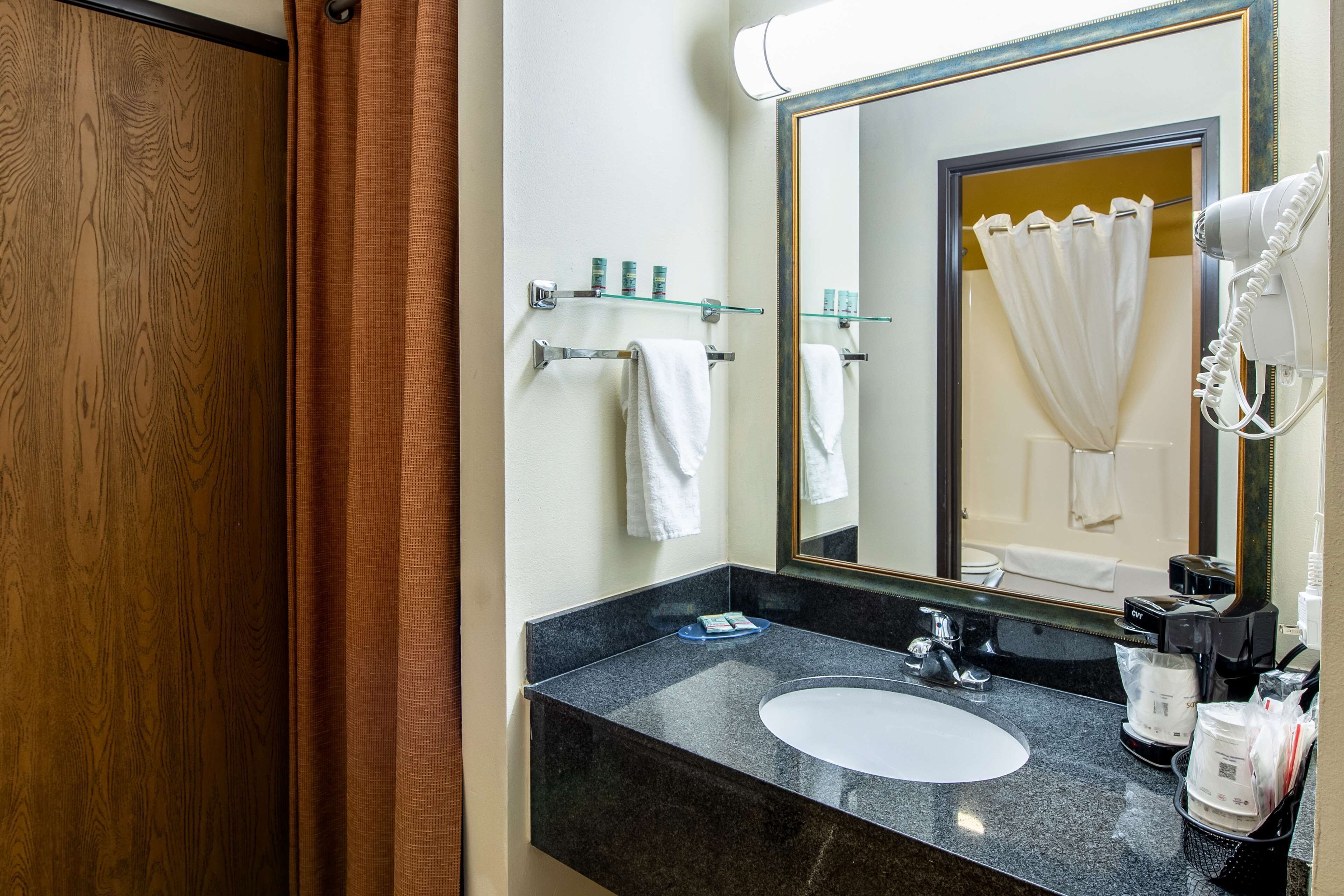 Un baño con un lavabo de granito negro, un espejo y una toalla blanca colgada en la pared.