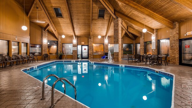 Una piscina interior con agua cristalina, rodeada de paredes de madera y un techo alto.