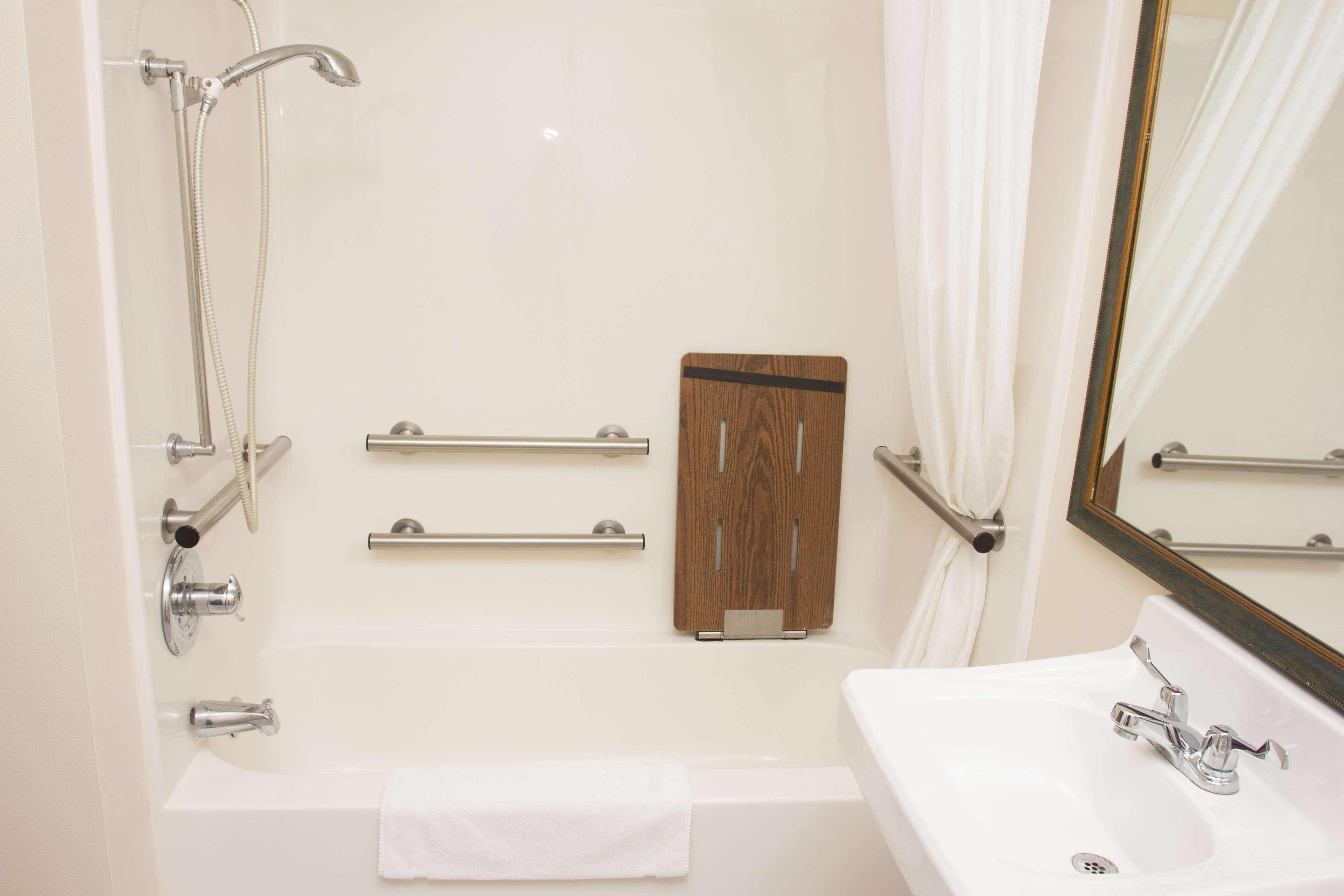 A bathroom with a bathtub, a sink, a mirror, and a shower.