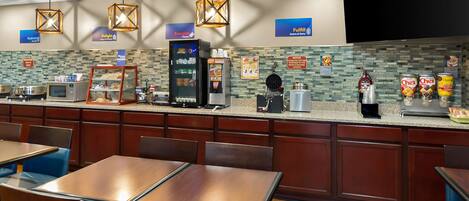 Restaurante de hotel con mostrador, zona de asientos y diversas opciones de comida y bebida.