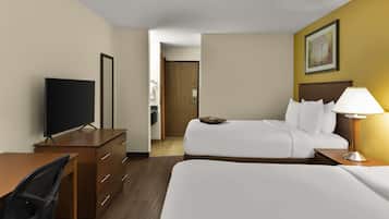Habitación de hotel con cama, escritorio, silla, televisión y mesita de noche con lámpara.