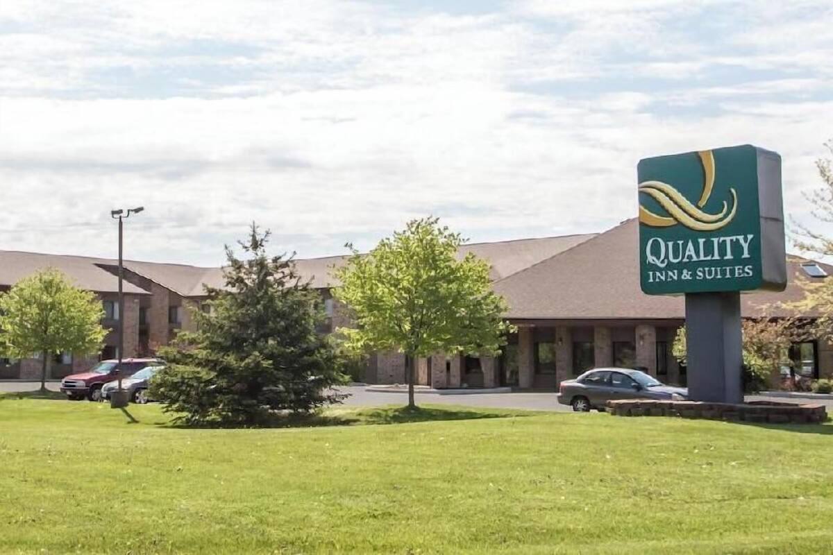 A Quality Inn & Suites with a large sign, a parking lot, and a grassy area.