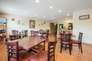 Comedor con varias mesas y sillas de madera, una cocina al fondo y un letrero que dice "BISTRO".