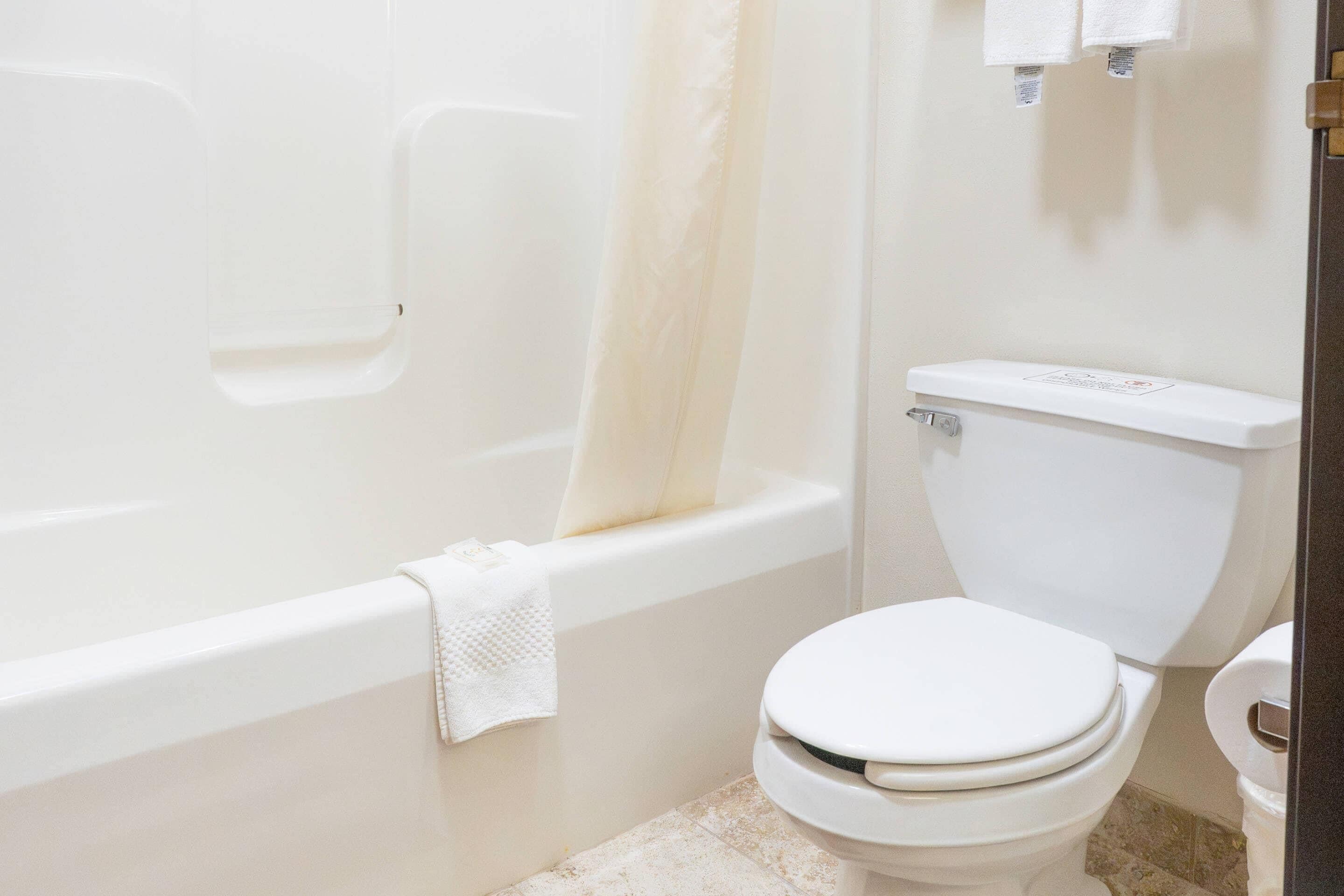 A bathroom with a bathtub, toilet, and shower curtain.