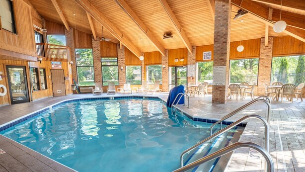 Una piscina interior con agua azul cristalina, rodeada de paredes de madera y grandes ventanales.
