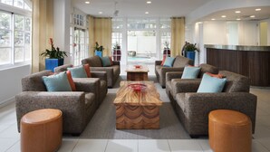 A spacious lobby with a central coffee table, four sofas with cushions, and potted plants. - Coconut Waikiki Hotel (Honolulu)