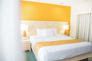 Ein Hotelzimmer mit Bett, zwei Nachttischlampen, einem Kopfteil mit kreisförmigen Mustern und einem Fenster mit Vorhängen.