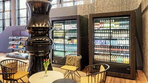 Un interior moderno con áreas de descanso, una gran escultura decorativa y dispensadores refrigerados de bebidas.