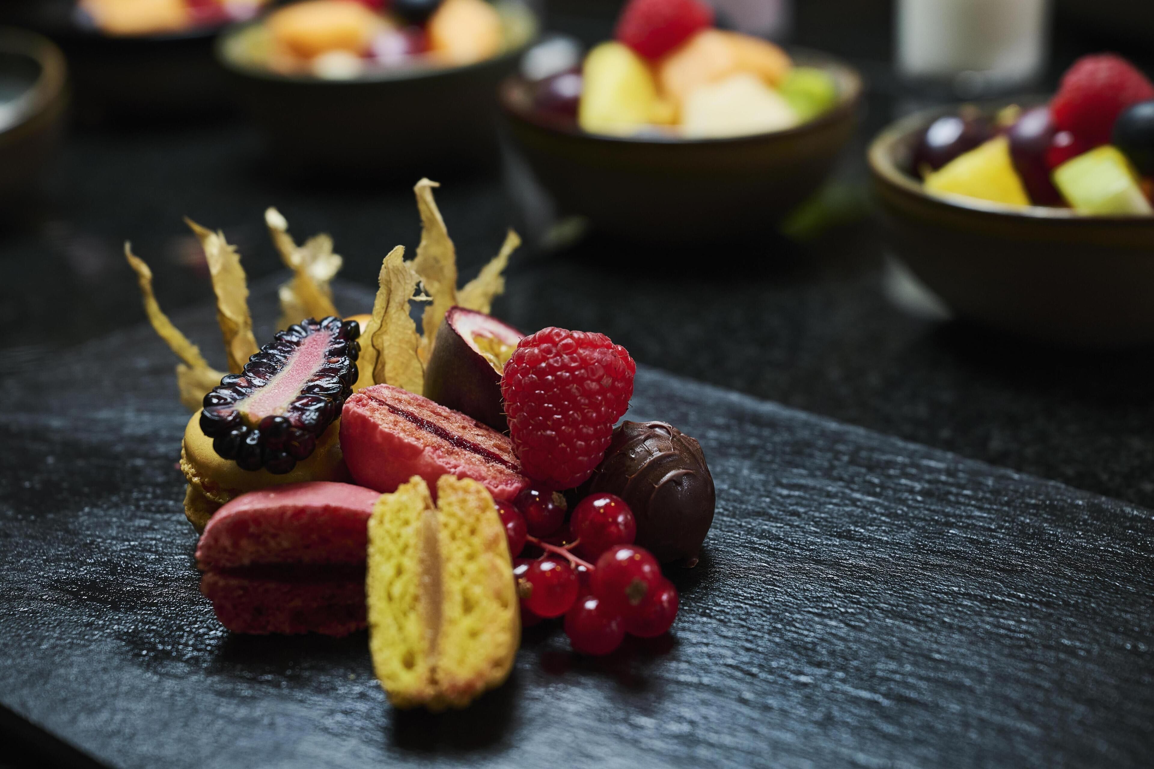 A selection of assorted fruits and pastries on a dark surface.