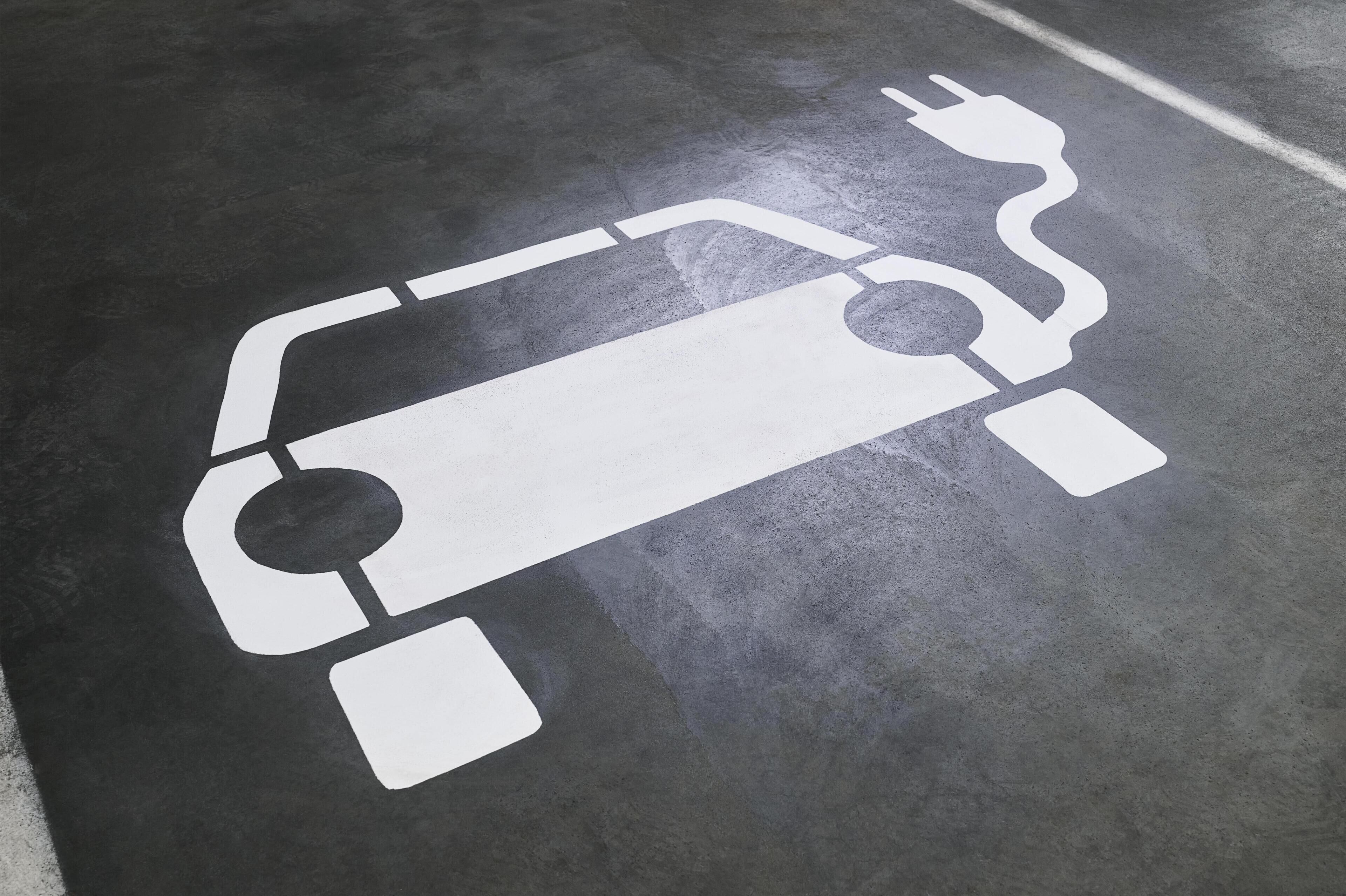 A parking space with a white electric vehicle charging symbol.