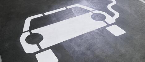A parking space with a white electric vehicle charging symbol.