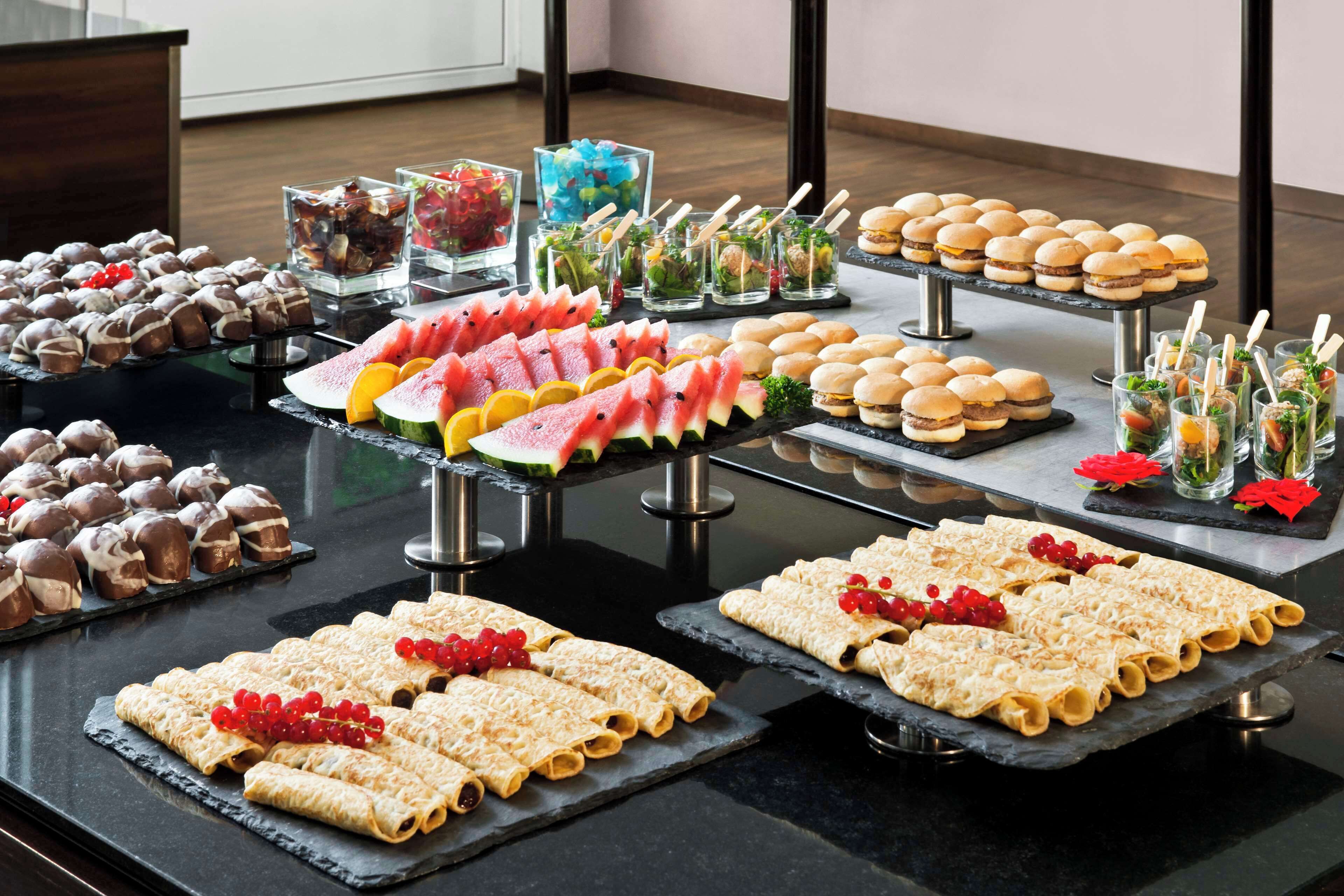 A buffet table with various food items including pastries, sandwiches, and fruit.