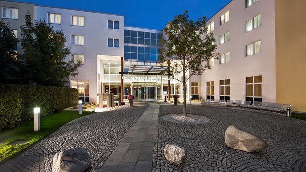 An airport hotel with a modern design, featuring a paved courtyard with rocks and a glass entrance. - NH Frankfurt Airport West (Raunheim)
