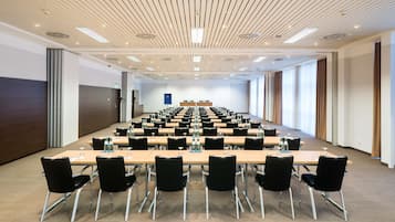 A conference room with a long table, black chairs, and a modern ceiling design.