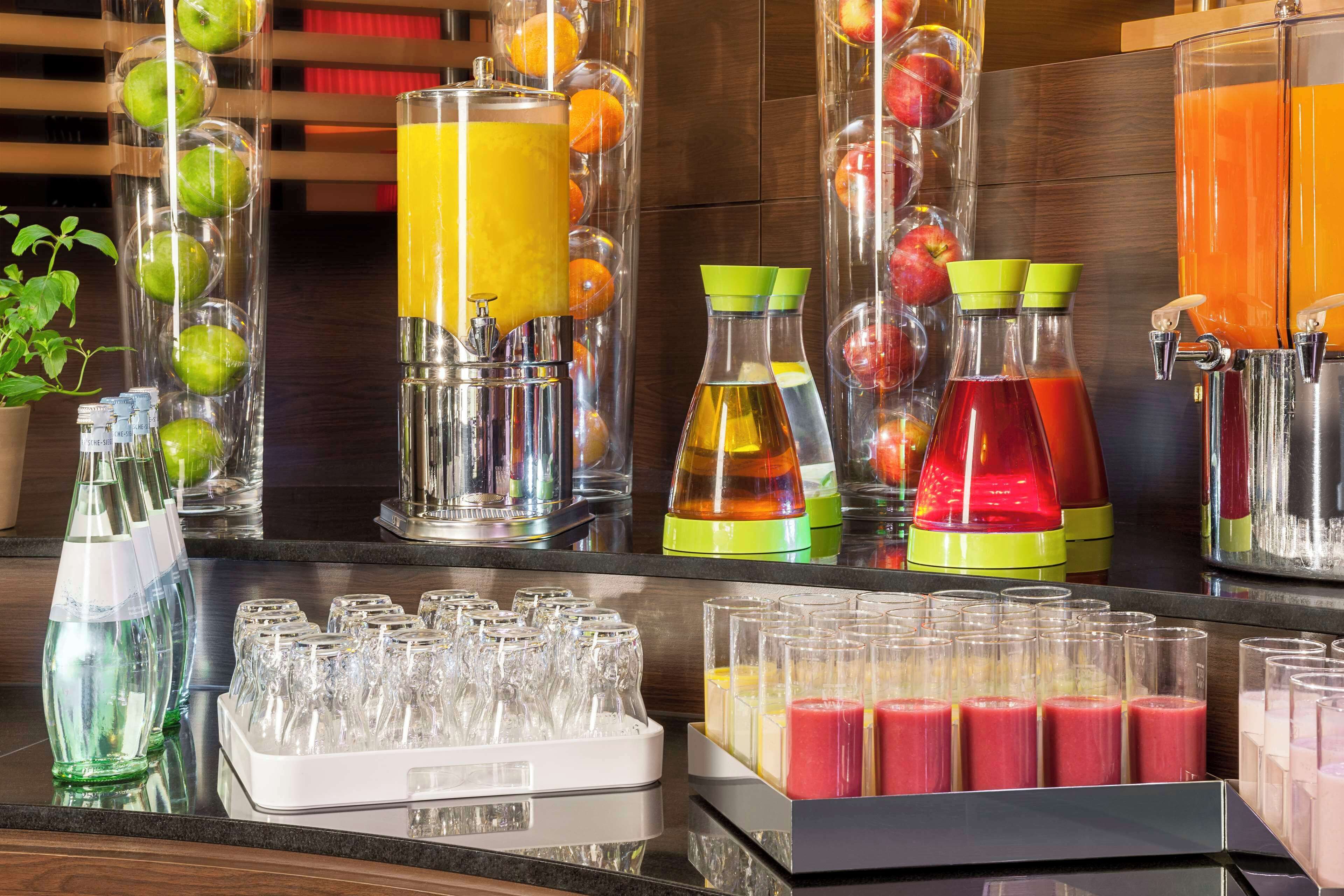 Un bar de zumos con diversas opciones de jugos de frutas y verduras, y una selección de vasos para servir.