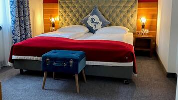 Ein Hotelzimmer mit einem großen Bett, roten Wänden, einem Stadtbildgemälde, zwei Nachttischlampen und einem blauen Koffer.