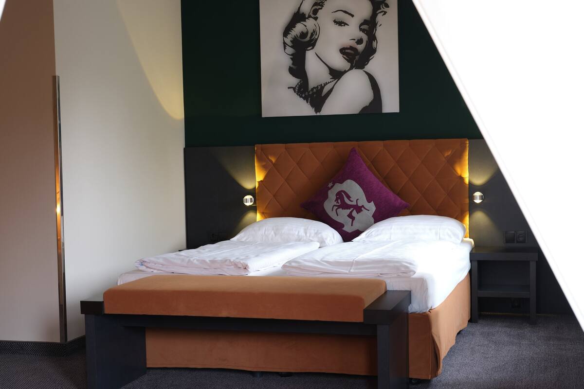 A modern bedroom with a bed, a headboard, a pillow, and a wall-mounted light fixture.