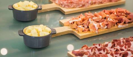 A buffet table with various food items and glasses of wine.