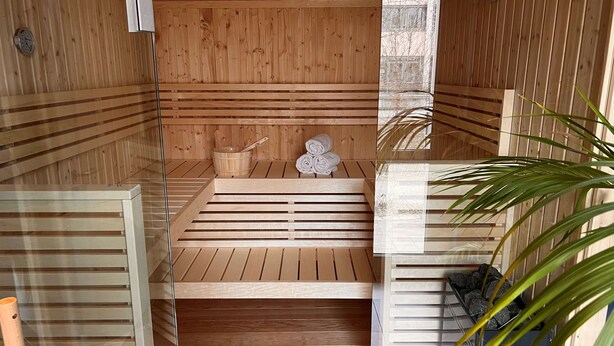 Una sauna con bancos de madera, un cubo de madera y toallas.