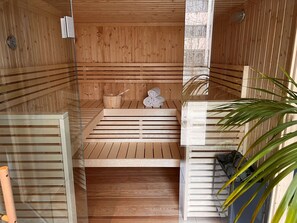 A sauna with wooden benches, a wooden bucket, and towels. - SCOTTY + PAUL Hotel Deggendorf (Deggendorf)