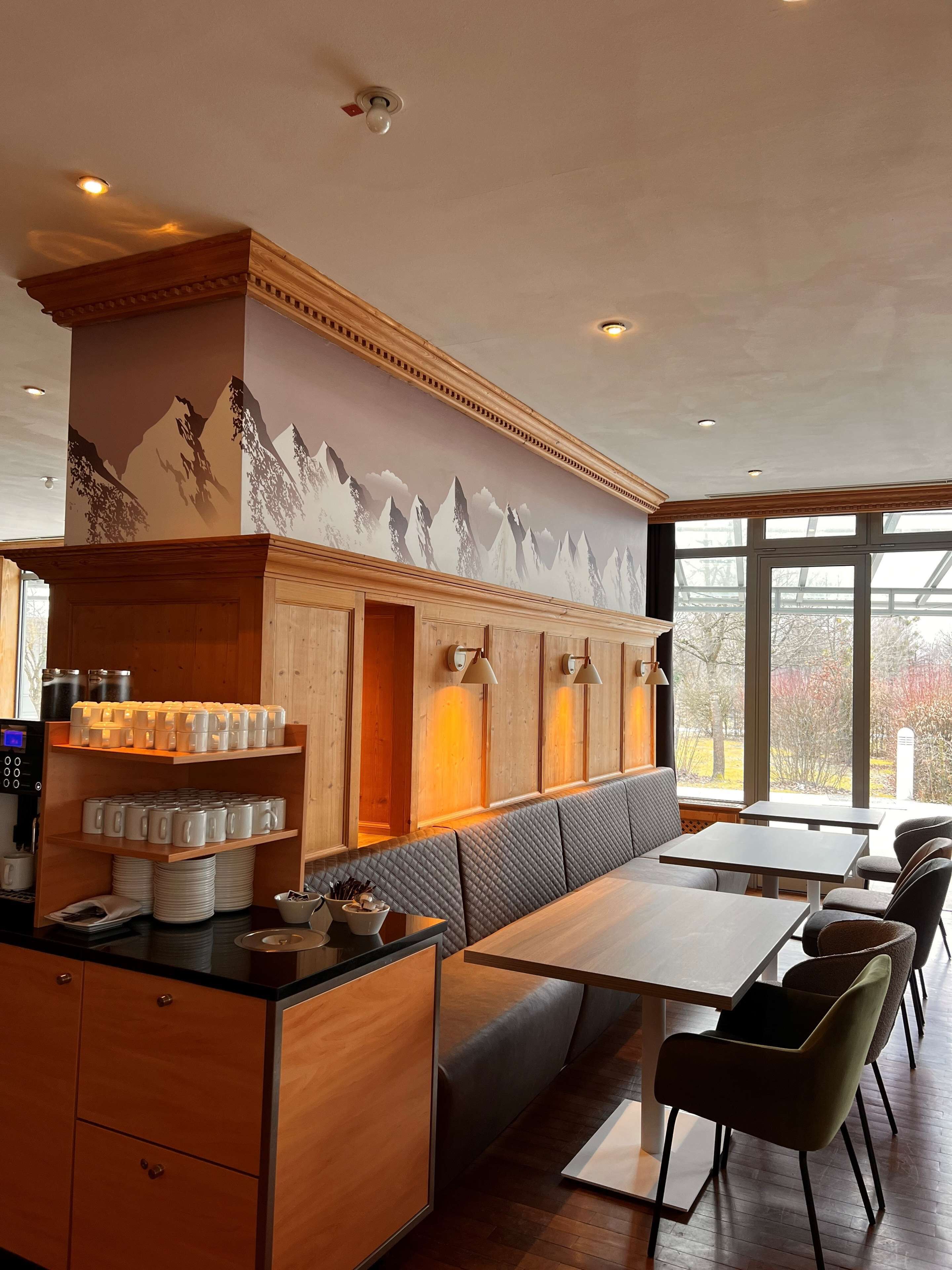 Un ristorante con mobili in legno, un murale raffigurante montagne e un'area con tavoli e sedie.