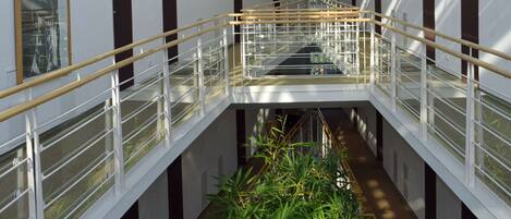 Un intérieur moderne avec un plafond en verre, un atrium central et un escalier.