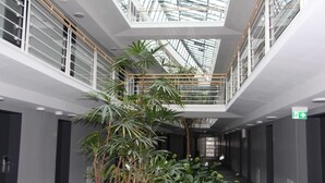 Un interior moderno con un atrio central, techo de cristal y plantas de interior.