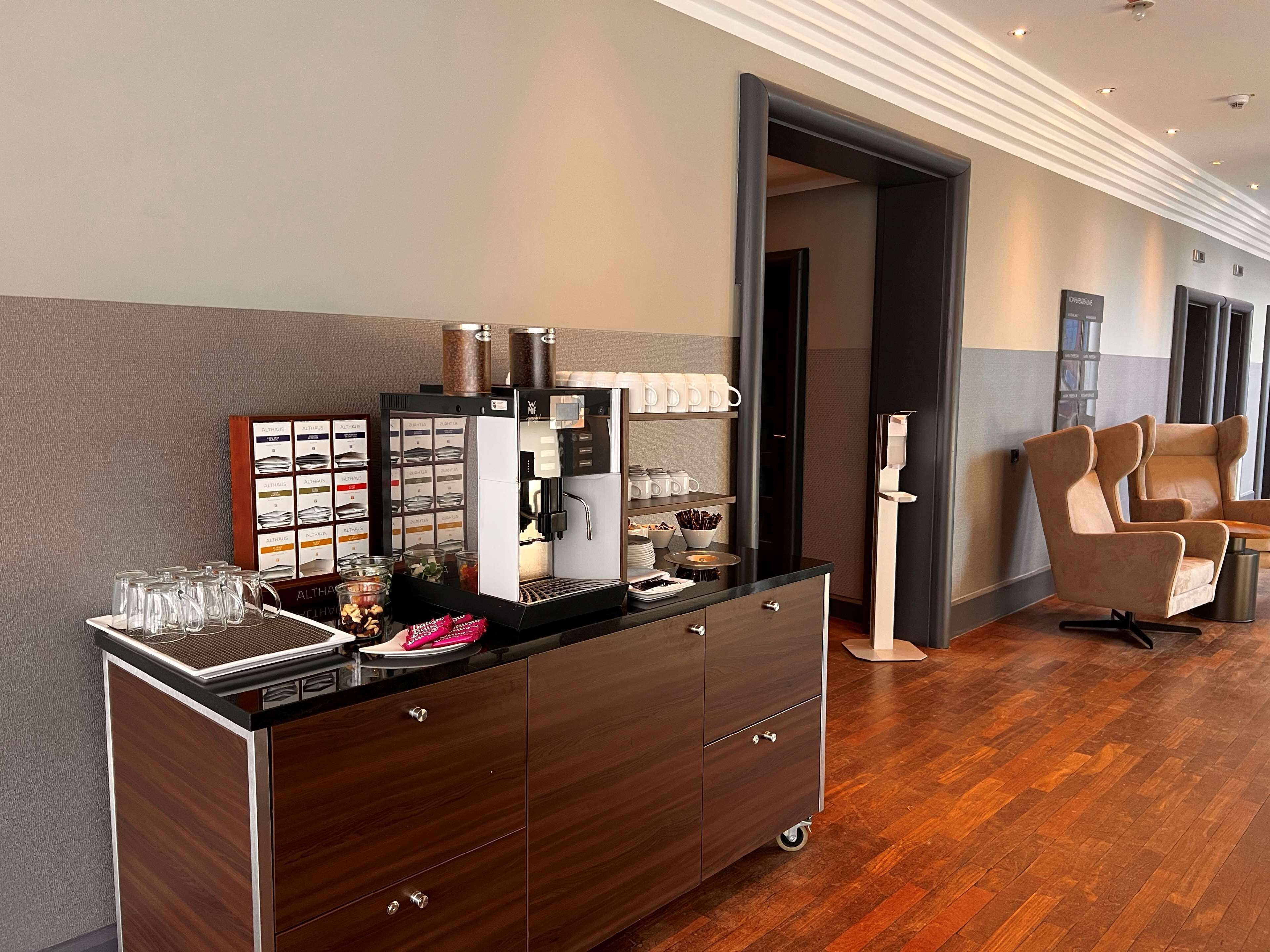 Ein modernes Hotelzimmer mit einer Kaffeestation, einer Sitzecke mit zwei Sesseln und Holzboden.