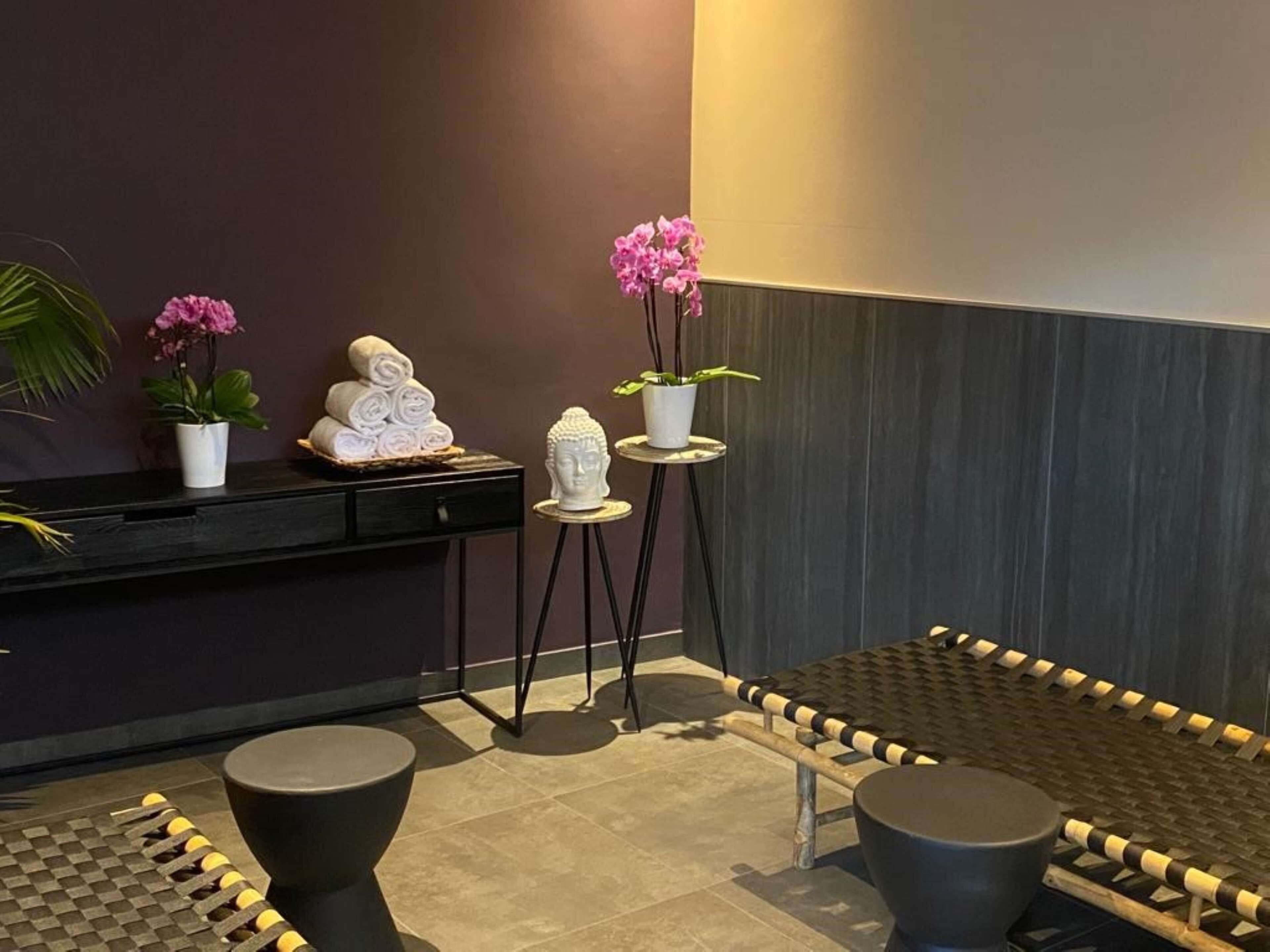 Ein Wellnessbereich mit einer Rezeption, einer Buddha-Statue und zwei Zimmerpflanzen.