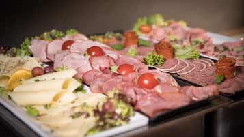 A buffet with various meats, cheeses, and vegetables.