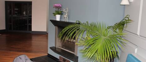 Una sala de estar moderna con chimenea, un sillón cómodo y una planta grande en maceta.